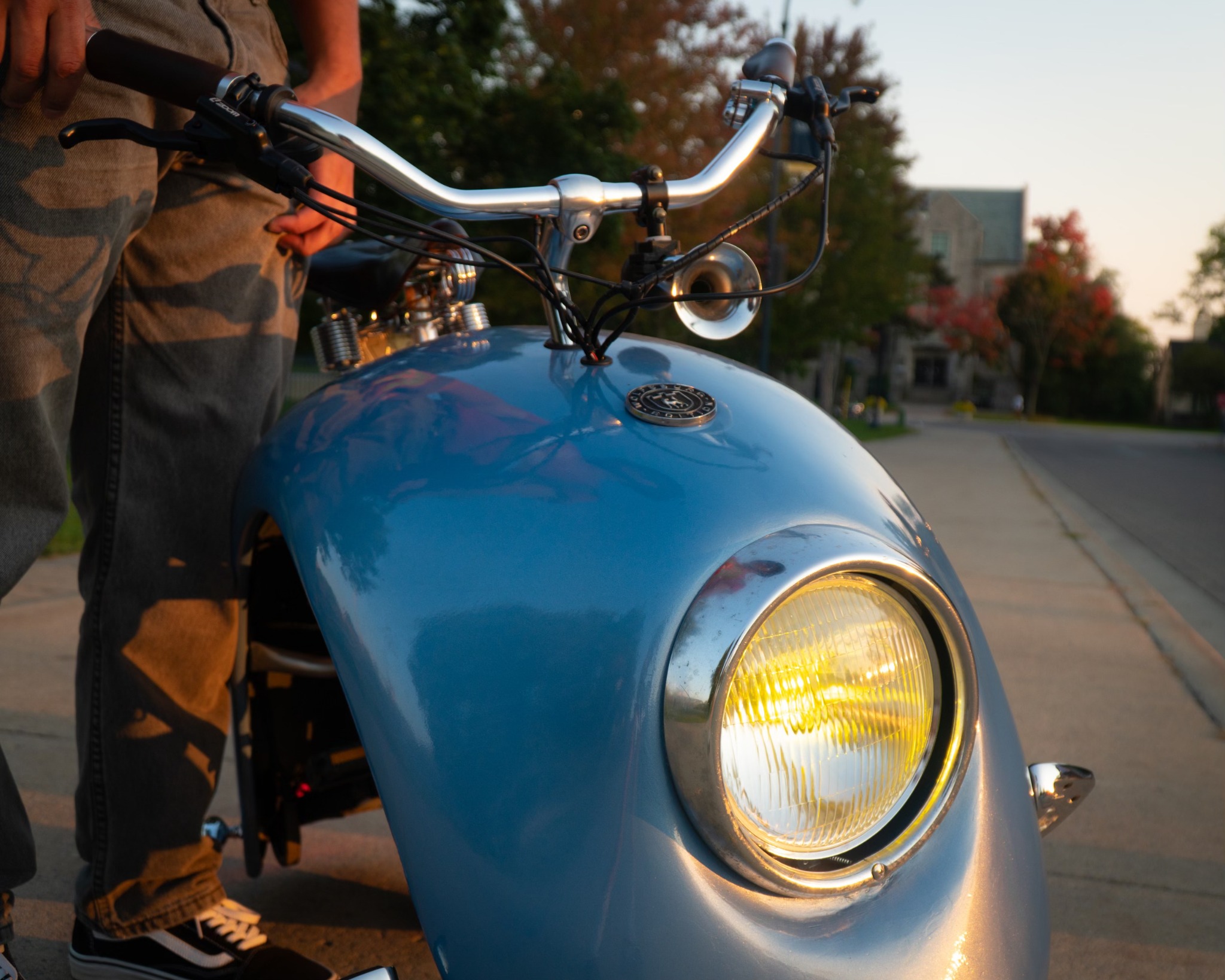 Close front view of the completed blue mini bike with its headlight illuminated