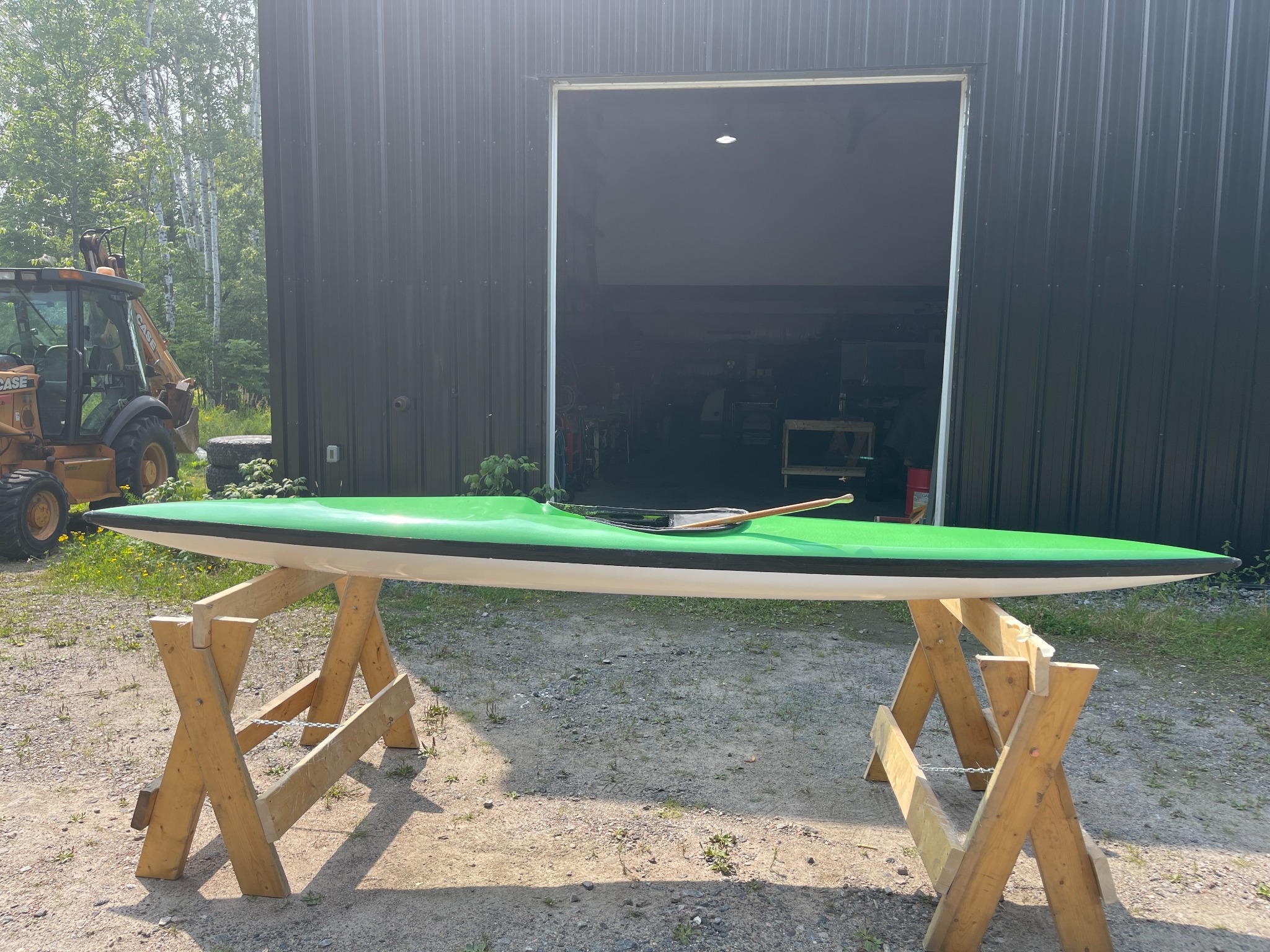 Completed green and white whitewater kayak resting on wooden stands
