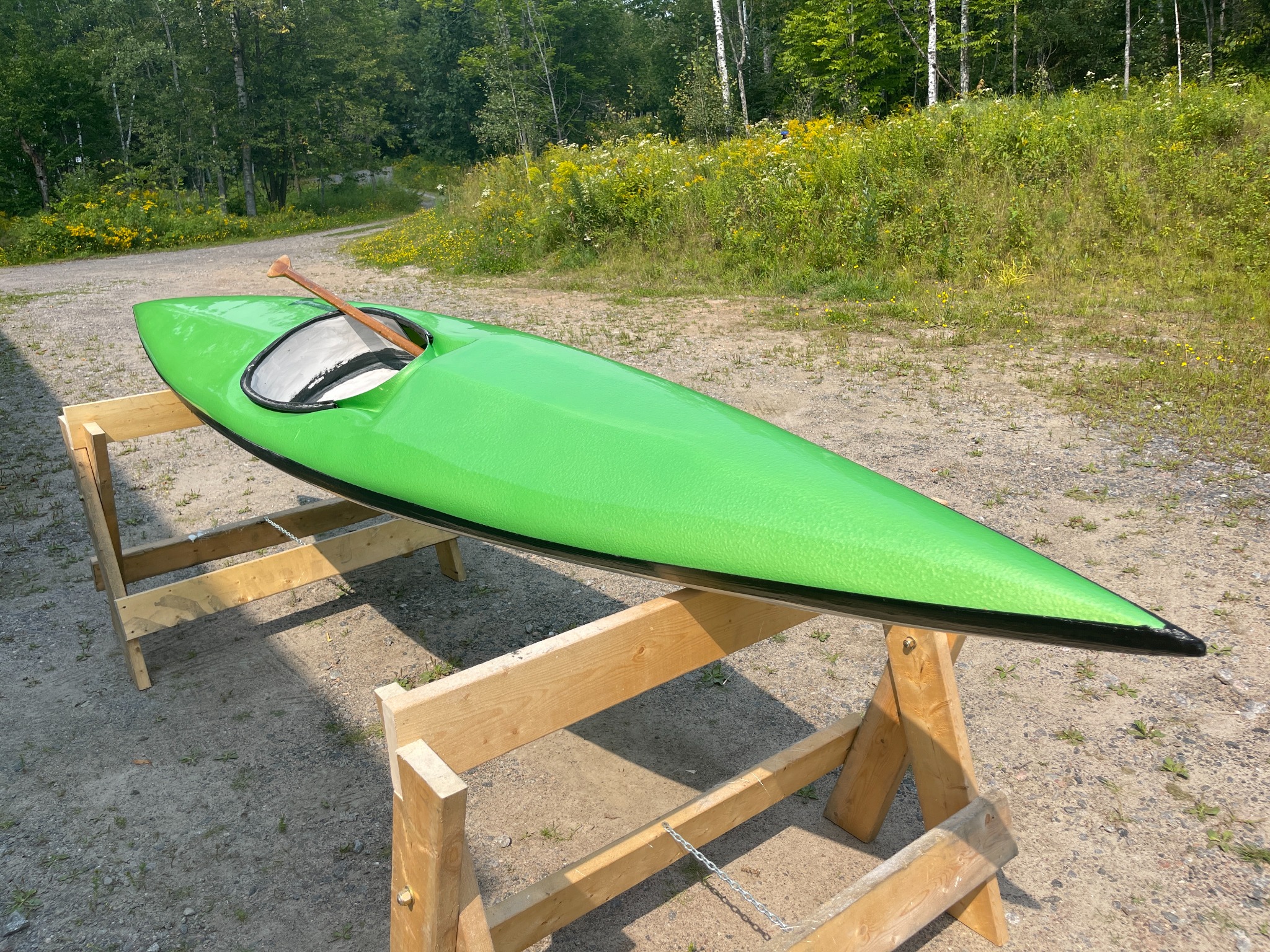 Completed green whitewater kayak photographed from a front-side angle